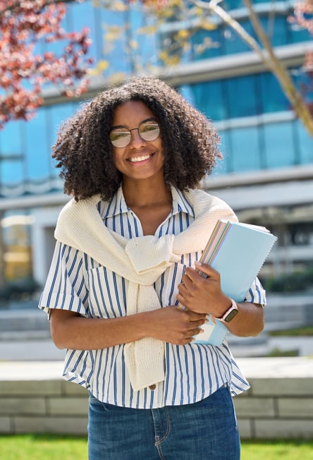 Woman Walking on Campus with Notebooks in Hands