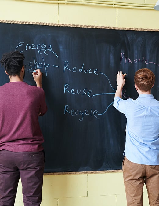 students writing on chalkboard