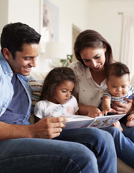FI-reading-hispanic-family-sitting-on-the-sofa reading-a-book-together.jpg