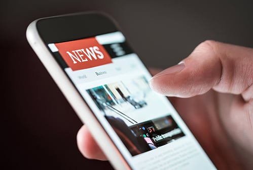 hand-holding-cell-mobile-phone-with-news-on-screen