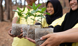 T-planting-trees-asian-students-holding-new-trees-in-containers-in-park.png